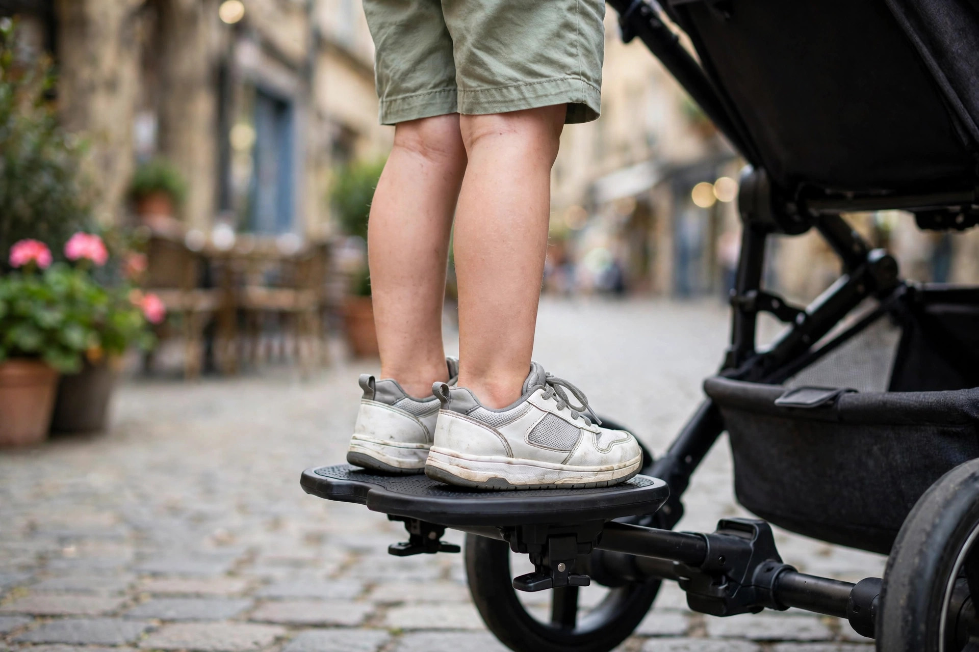 Best Travel Stroller for Two Kids 13 Close-up of a toddler standing on a rider board attachment clipped to a travel stroller